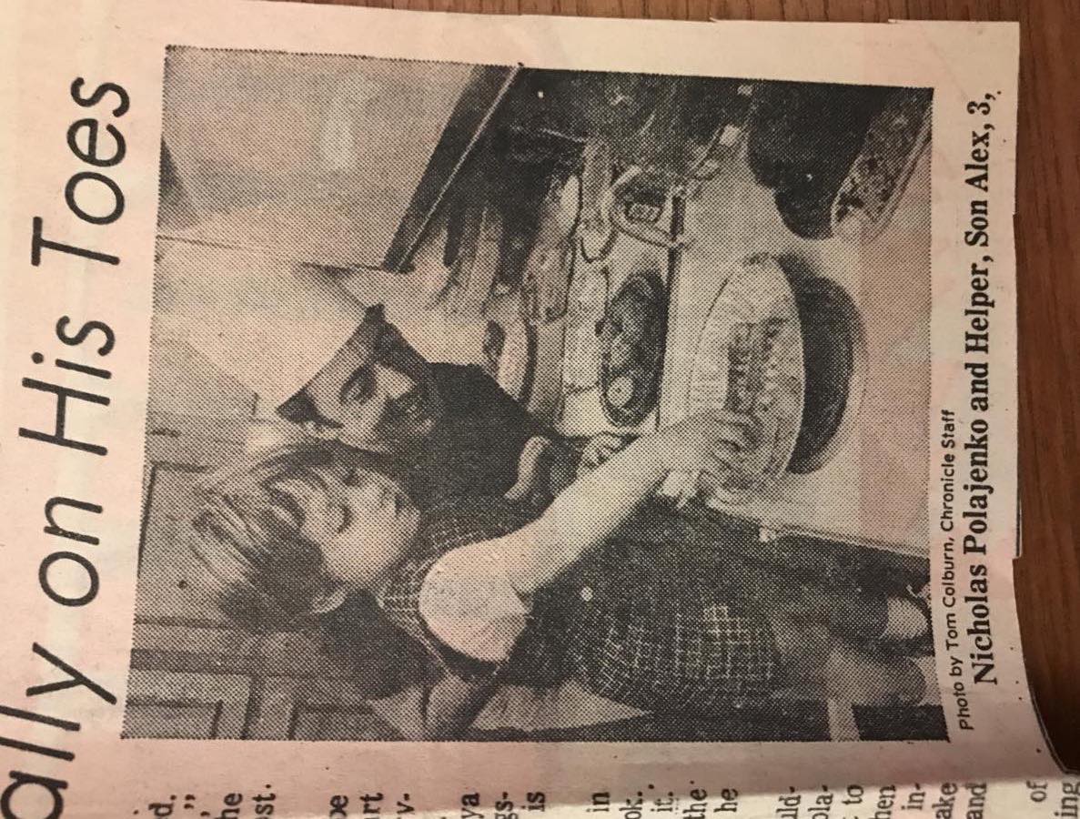Newspaper clipping showing Nicholas Polajenko in a chef's hat at a kitchen counter beside his three-year-old son Alex, who is reaching into a pie dish